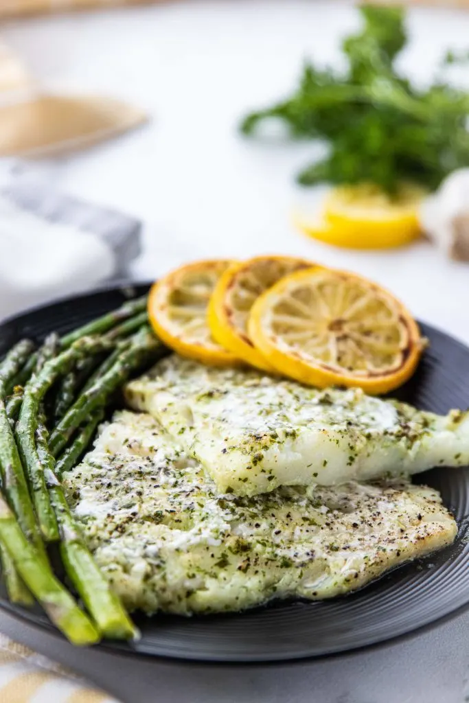 This lemon and herb marinated easy keto baked cod is perfect for a Spring dinner. This easy keto sheet pan dinner is both budget and kid friendly AND its ready in under 20 minutes! 