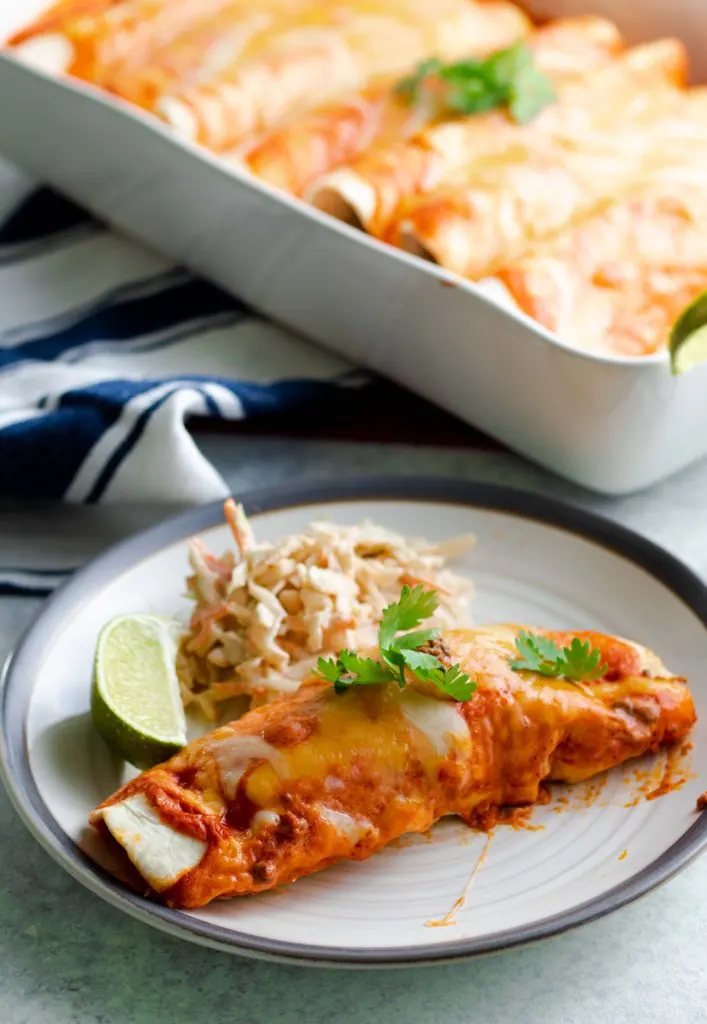 Low carb beef enchiladas with chipotle lime coleslaw and a lime wedge.