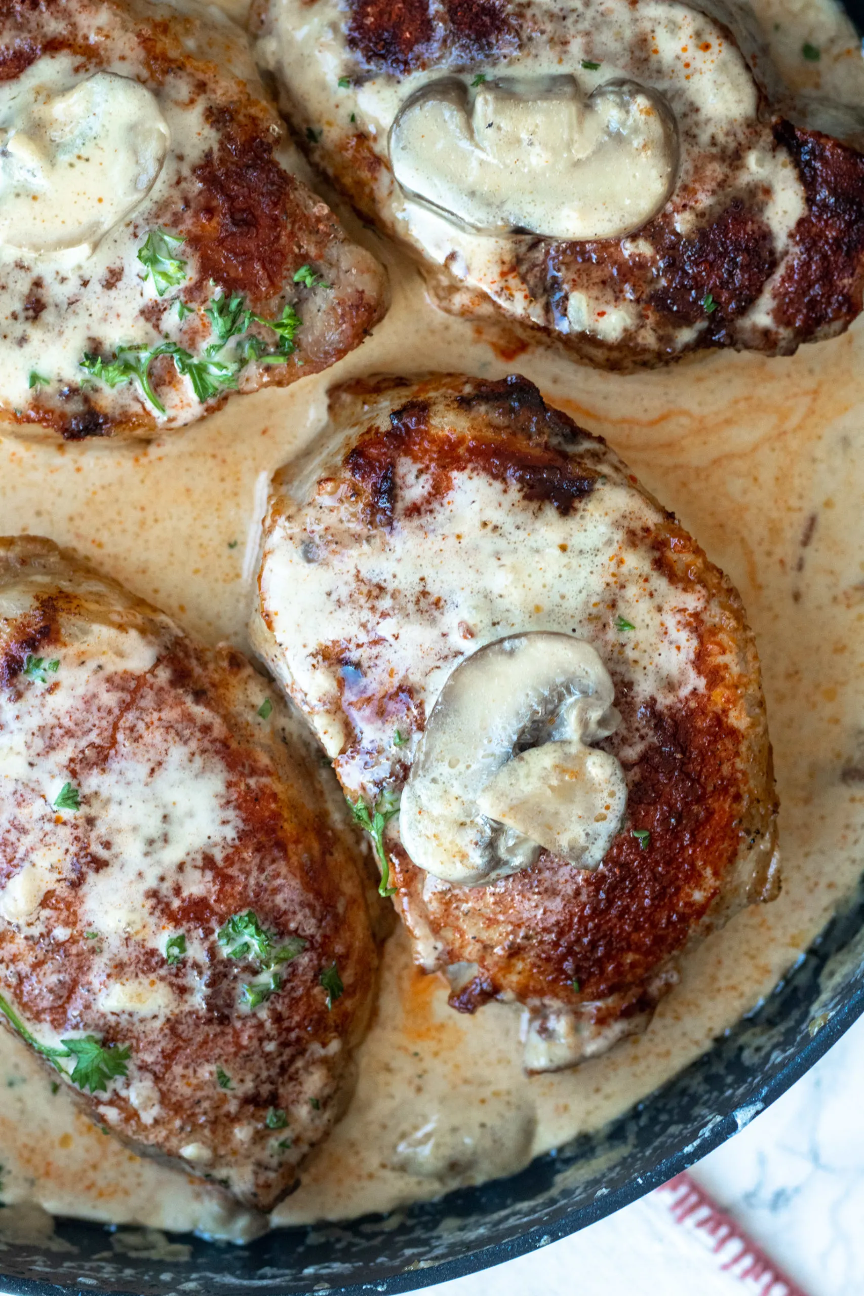 Thick cut boneless pork chops are seasoned and baked in the oven before getting smothered in a bacon and mushroom cream sauce. This easy keto smothered pork chops recipe is a crowd pleaser for all. 