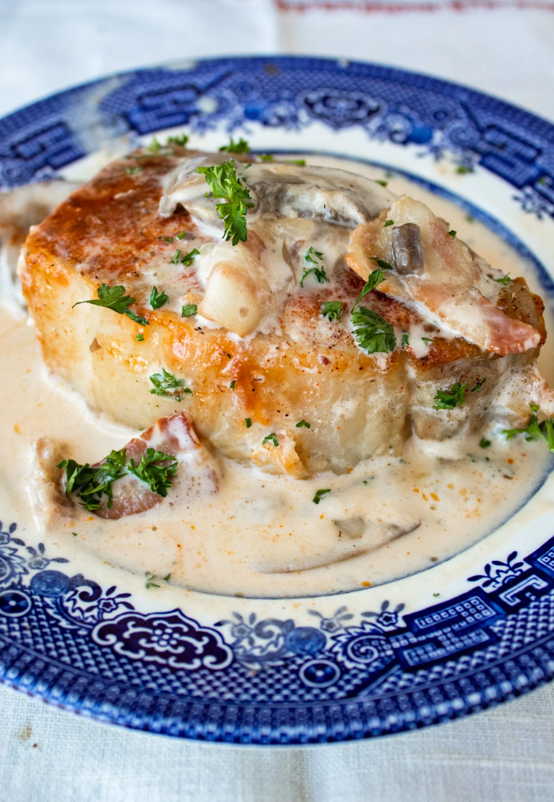 Smothered pork chop with bacon, mushrooms, and garlic in a cream sauce.