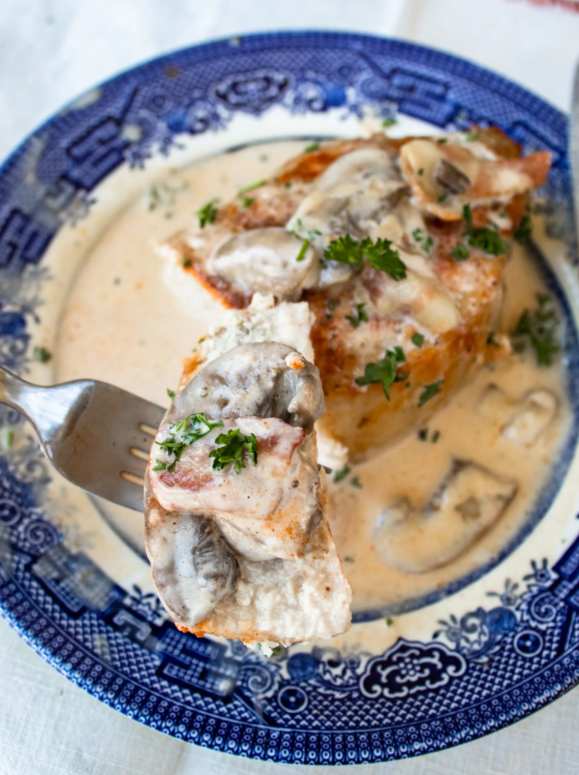 Thick cut boneless pork chops are seasoned and baked in the oven before getting smothered in a bacon and mushroom cream sauce.