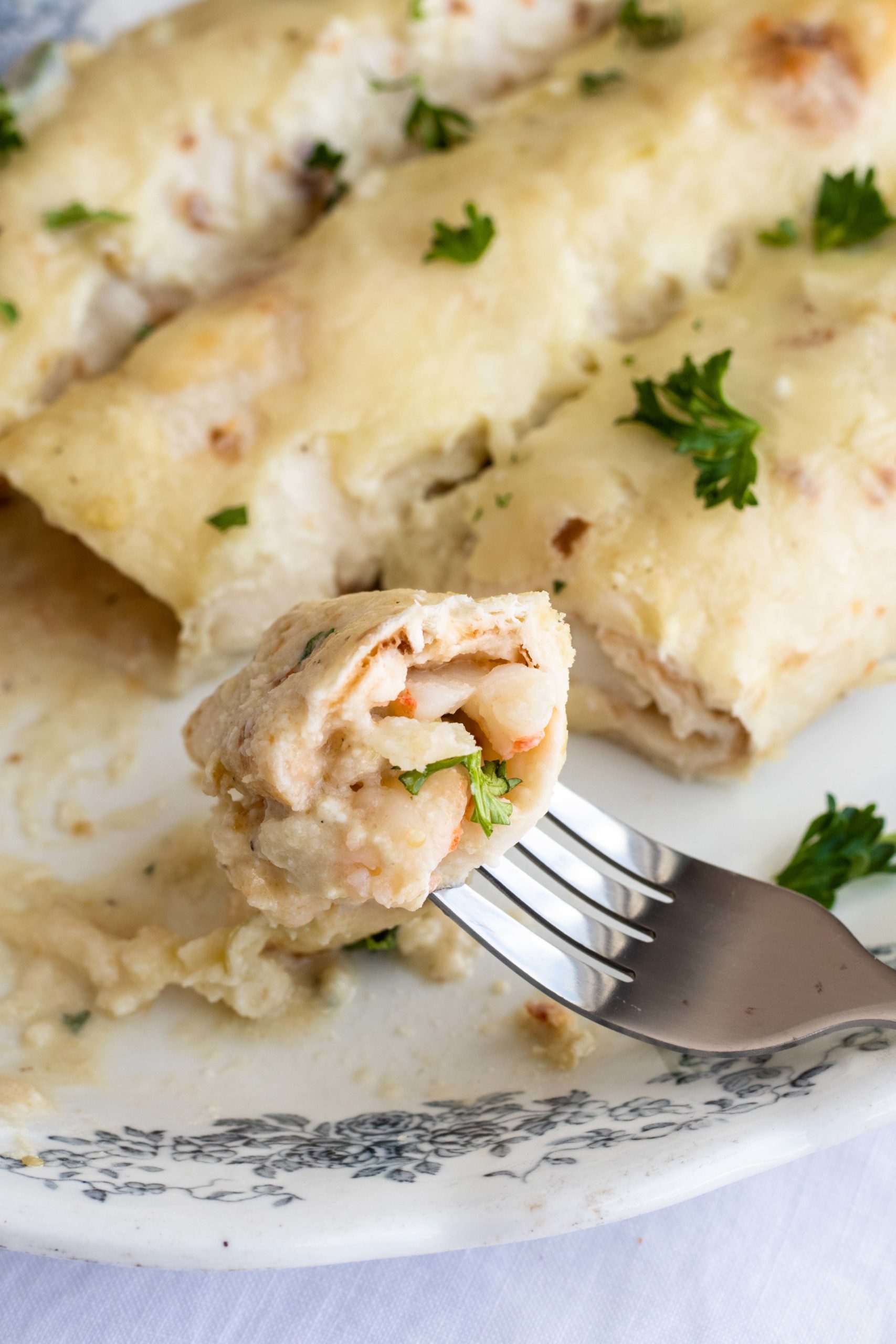 Bite of low carb shrimp enchilada with cheese sauce.