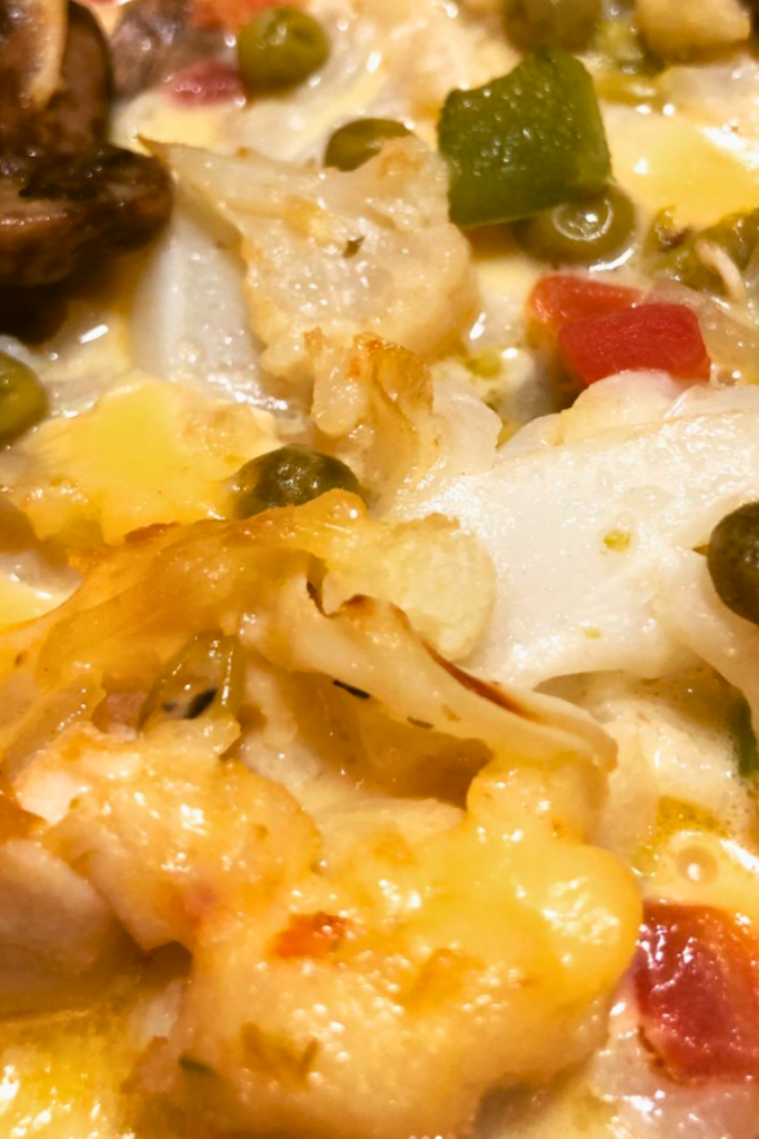 close up of chicken casserole with mushrooms, cauliflower and green peas