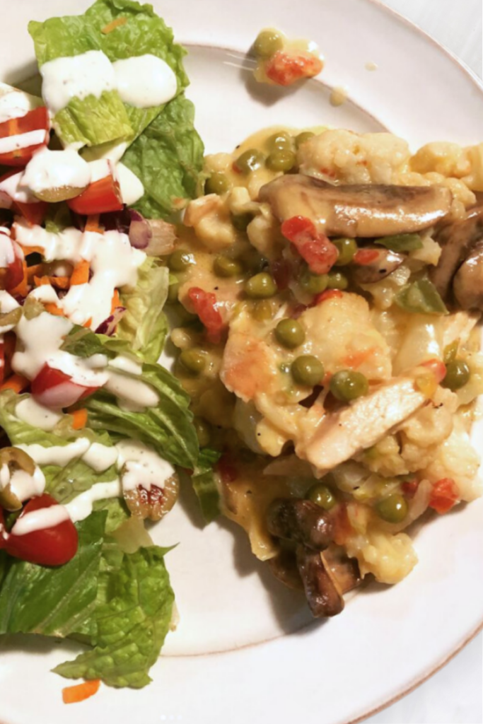plate with salad and a serving of chicken casserole with mushrooms, cauliflower and green peas